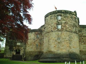 Skipton Castle: Photograph of the exterior of the inner bailey entrance, showing two of the inner curtain's towers. The entrance is obscured by a Tudor porch
